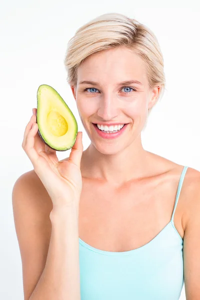 Mooie blonde houden de helft van een avocado — Stockfoto