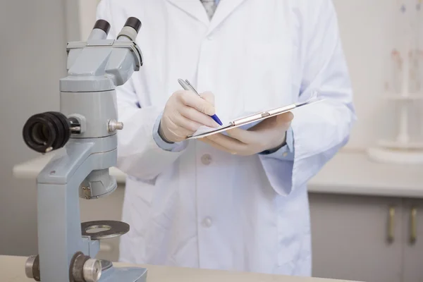 Científico escribiendo en portapapeles — Foto de Stock