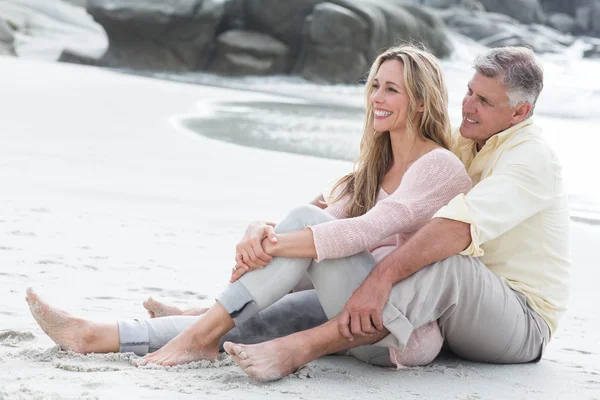 Joyeux couple assis sur le sable — Photo