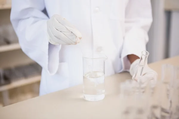 Cientista examinando tubo de ensaio e copo — Fotografia de Stock