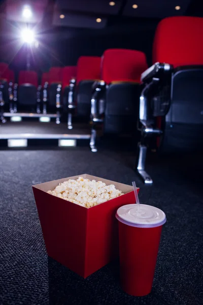 Empty rows of red seats with pop corn and drink on the floor — Stock Photo, Image