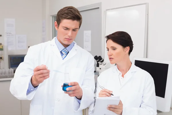 Scientists examining attentively pipette with fluid — Stock Photo, Image