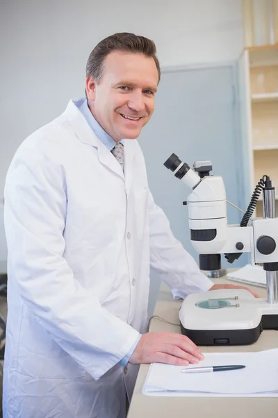 Cientista sorridente examinando amostra com microscópio — Fotografia de Stock