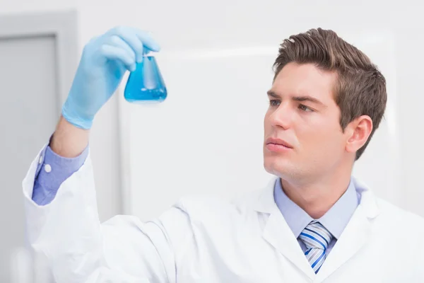 Scientist looking attentively at the beaker — Stock Photo, Image