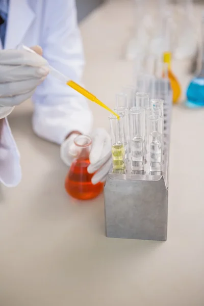 Wissenschaftler gießt orangefarbene Flüssigkeit ins Reagenzglas — Stockfoto