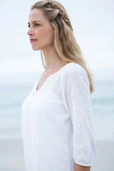 Mujer rubia sonriente de pie junto al mar — Foto de Stock