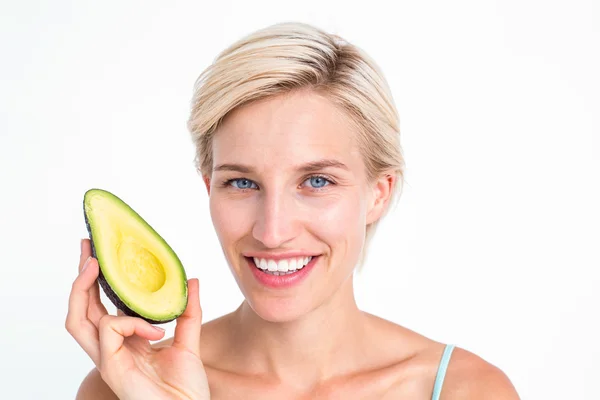 Mooie blonde houden de helft van een avocado — Stockfoto