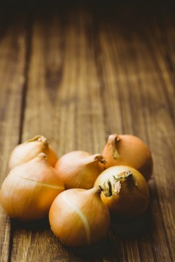 Fresh onions on wooden background clipart