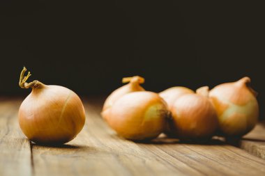 Fresh onions on wooden background clipart
