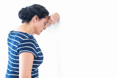 Sad woman leaning against the wall clipart