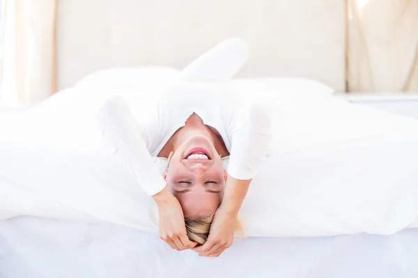 Smiling blonde woman lying on bed — Stock Photo, Image