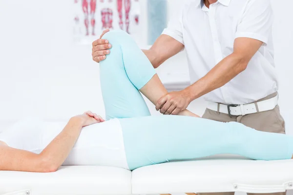 Doctor stretching his patients leg — Stock Photo, Image