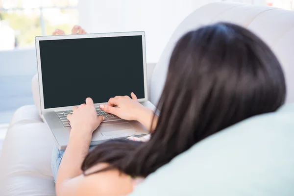 Ładna brunetka za pomocą laptopa na kanapie — Zdjęcie stockowe