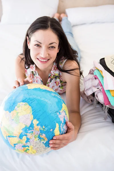 Brünette hält einen Globus auf dem Bett — Stockfoto