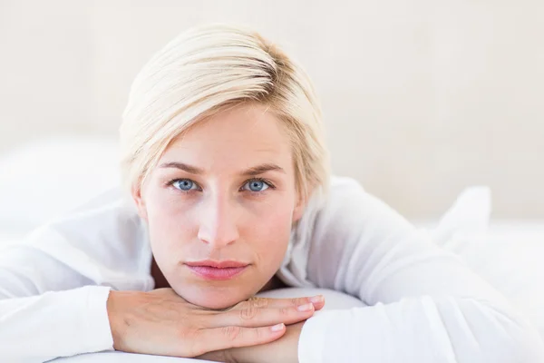 Lachende blonde vrouw liggend op het bed — Stockfoto