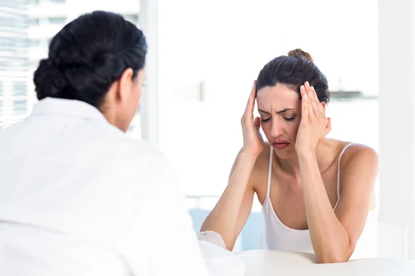 Woman grimacing in front of her doctor — Stock Photo, Image