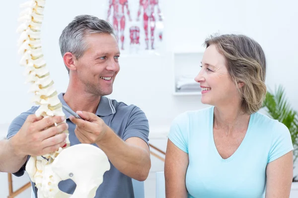 Fisioterapeuta mostrando modelo de columna vertebral a su paciente —  Fotos de Stock