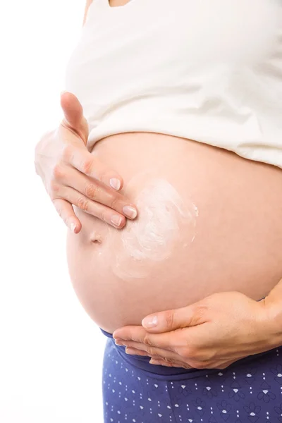 Zwangere vrouw met crème op hobbel — Stockfoto