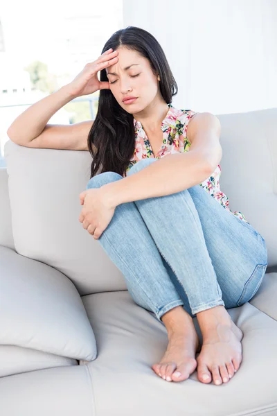 Půvabná brunetka s bolestí hlavy na gauči — Stock fotografie