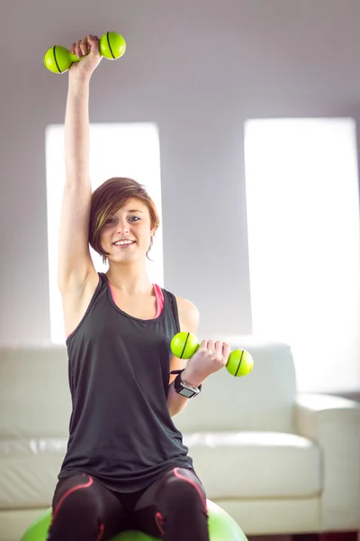 Fit femme soulevant haltère assis sur la balle — Photo