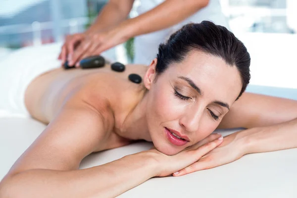 Sorrindo morena recebendo massagem de pedra quente — Fotografia de Stock