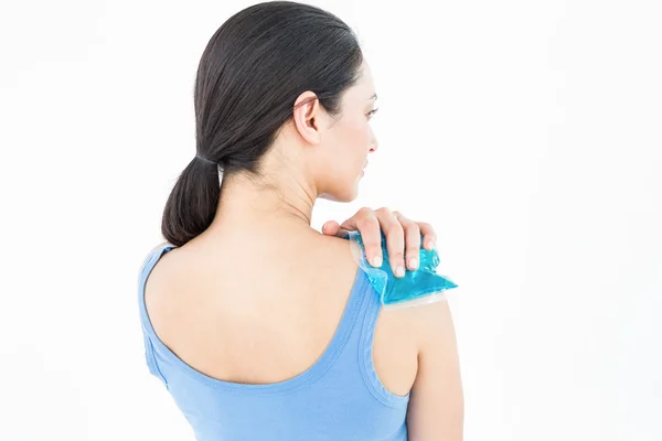 Brunette putting gel pack on shoulder — Stock Photo, Image