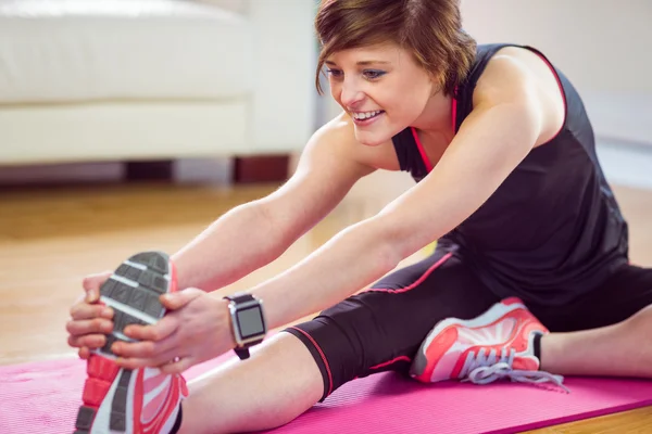 Fitte Frau dehnt sich auf der Gymnastikmatte — Stockfoto