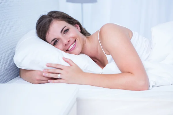 Žena se usmívá na kameru v posteli — Stock fotografie