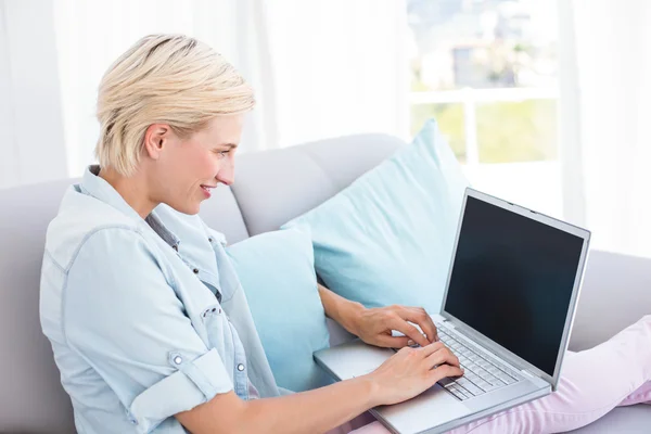 Mulher loira usando laptop no sofá — Fotografia de Stock