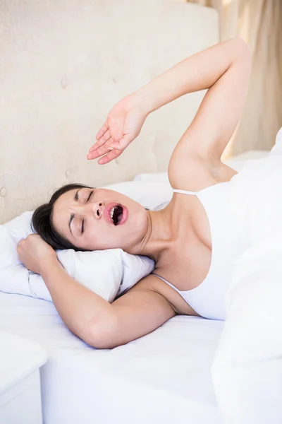 Pretty brunette yawning on bed — Stock Photo, Image