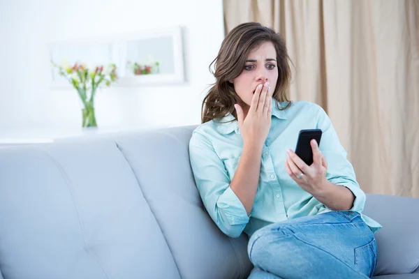 Surprised brunette looking at her smartphone — Stock Photo, Image