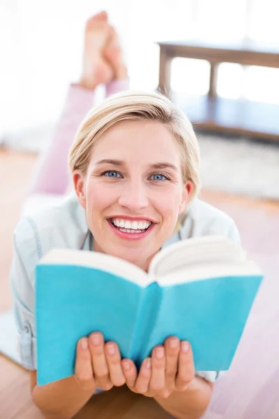 Blonde vrouw op de verdieping lezen van een boek — Stockfoto