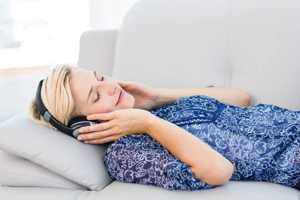 Ξανθιά γυναίκα ακούγοντας μουσική στον καναπέ — Φωτογραφία Αρχείου
