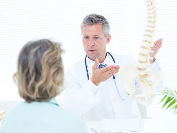 Doctor mostrando modelo de columna vertebral a su paciente — Foto de Stock