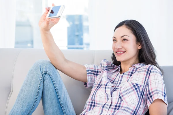 Jolie brune prenant un selfie sur le canapé — Photo