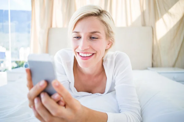 Blonde lying and texting with phone — Stock Photo, Image