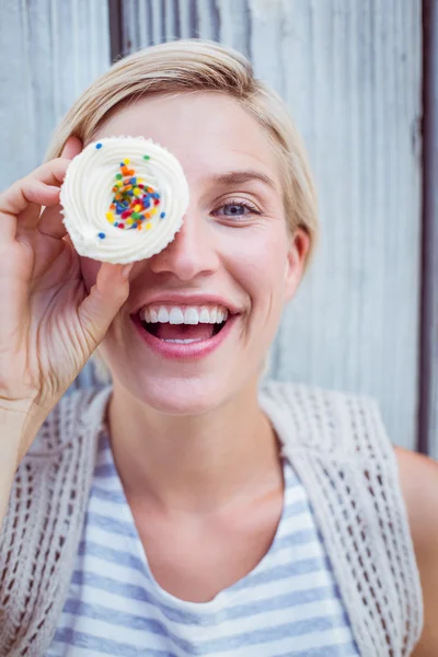 Söt blond kvinna grimaserande med cupcake — Stockfoto