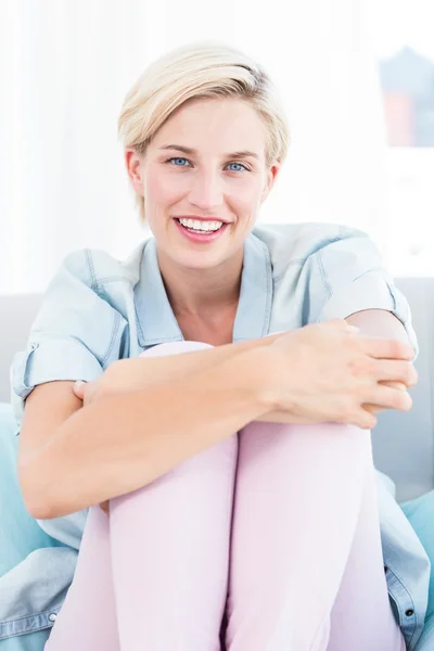 Pretty blonde woman sitting on the couch — Stock Photo, Image