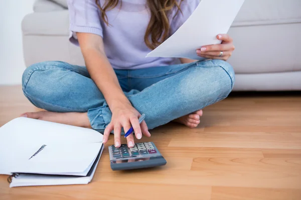 Woman calculating receipts on the floor — Stock Photo, Image