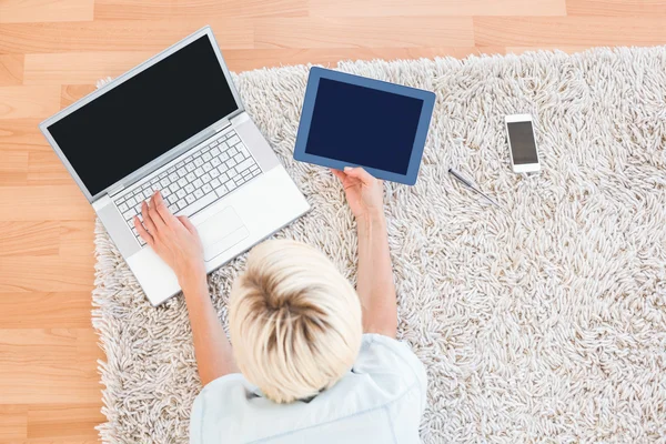 Woman on the floor using her laptop and tablet — Stock Photo, Image