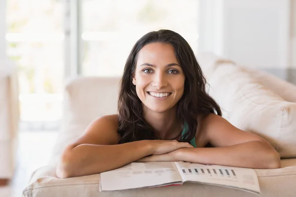 Brunette reading magazine on the couch — Stock Photo, Image