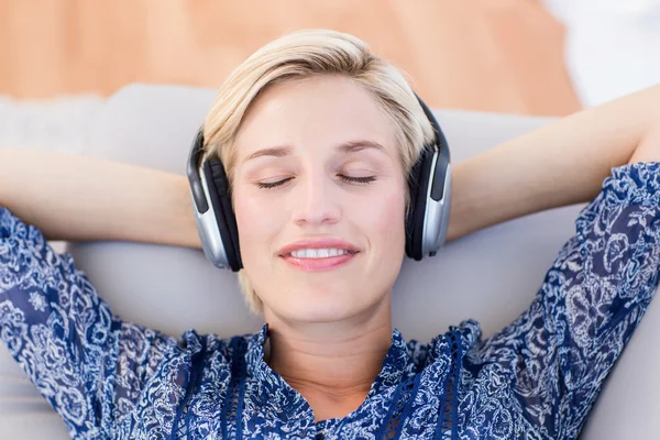 Blond kvinna lyssnar musik på soffan — Stockfoto