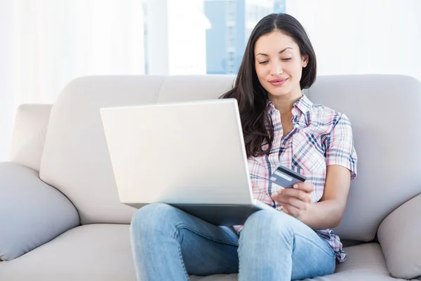 Mooie brunette zittend op de Bank en online winkelen — Stockfoto