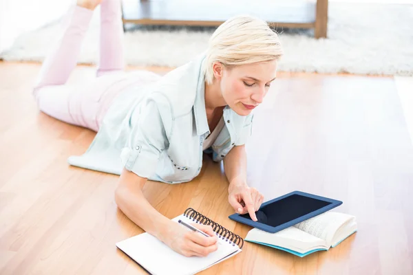 Mulher loira no chão tomando notas — Fotografia de Stock