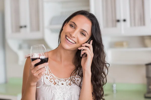 Söt brunett på telefonen med glas vin — Stockfoto