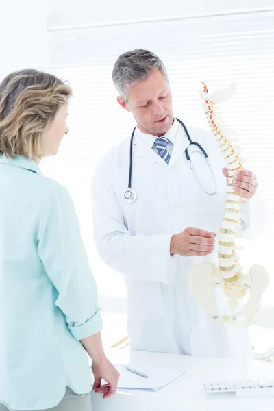 Doctor conversando con su paciente y mostrando la columna vertebral mo — Foto de Stock