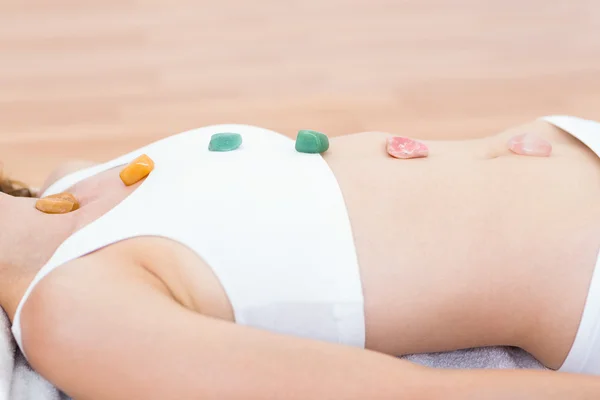 Relaxed brunette lying on mat with stones — Stock Photo, Image