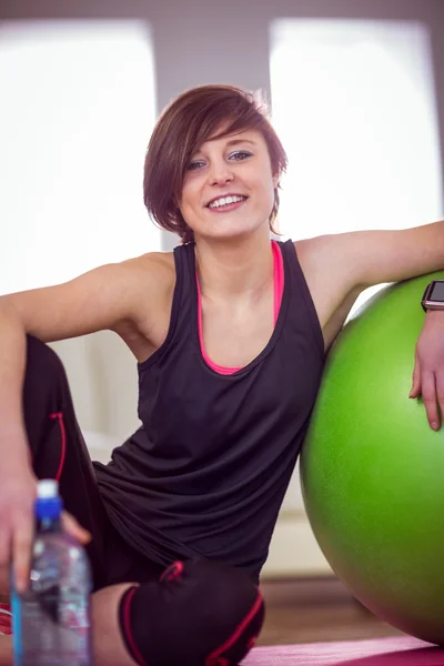 Mujer en forma sentada al lado de la pelota de ejercicio — Foto de Stock