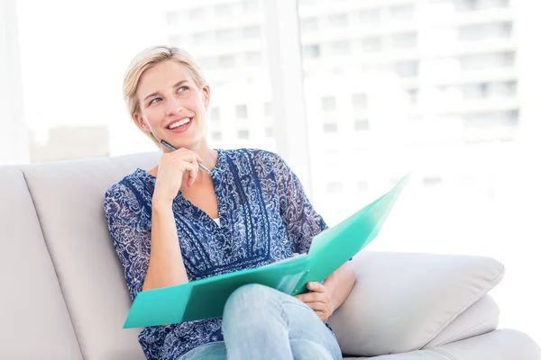 Blonde woman taking notes on the couch — Stock Photo, Image