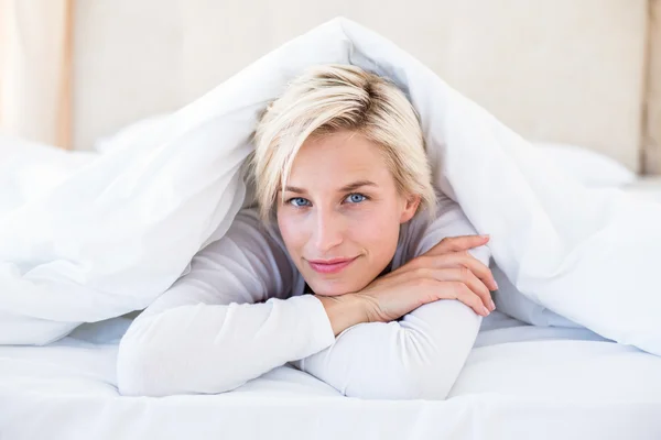 Sorridente donna bionda sdraiata sul letto — Foto Stock